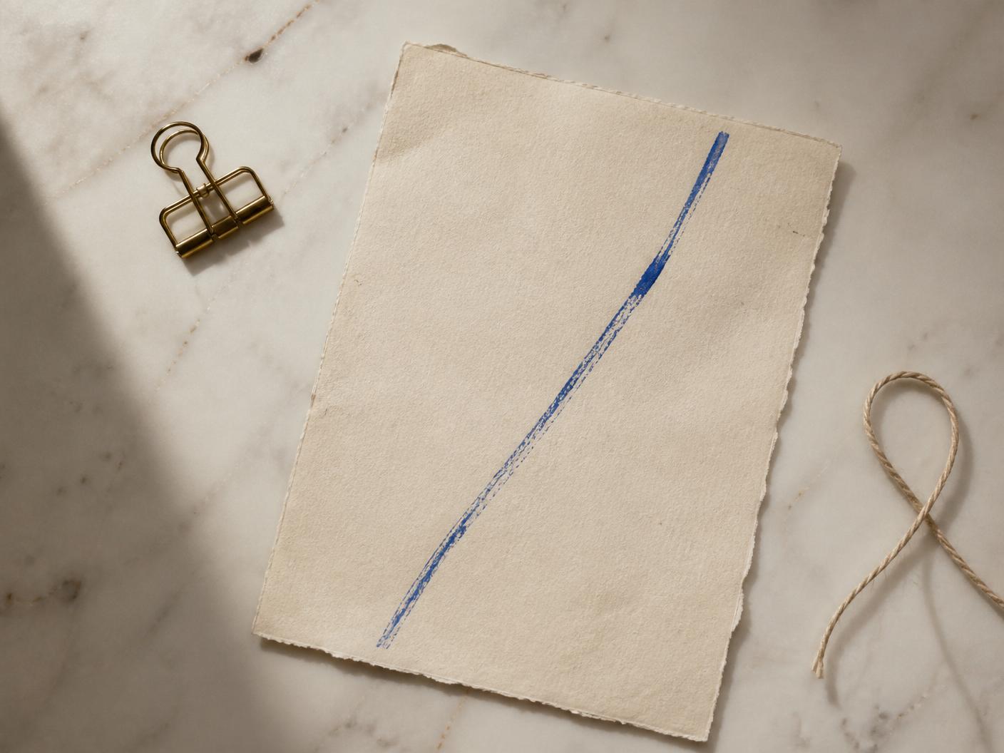 Still life of handmade paper with a Grecian Blue brushstroke on marble